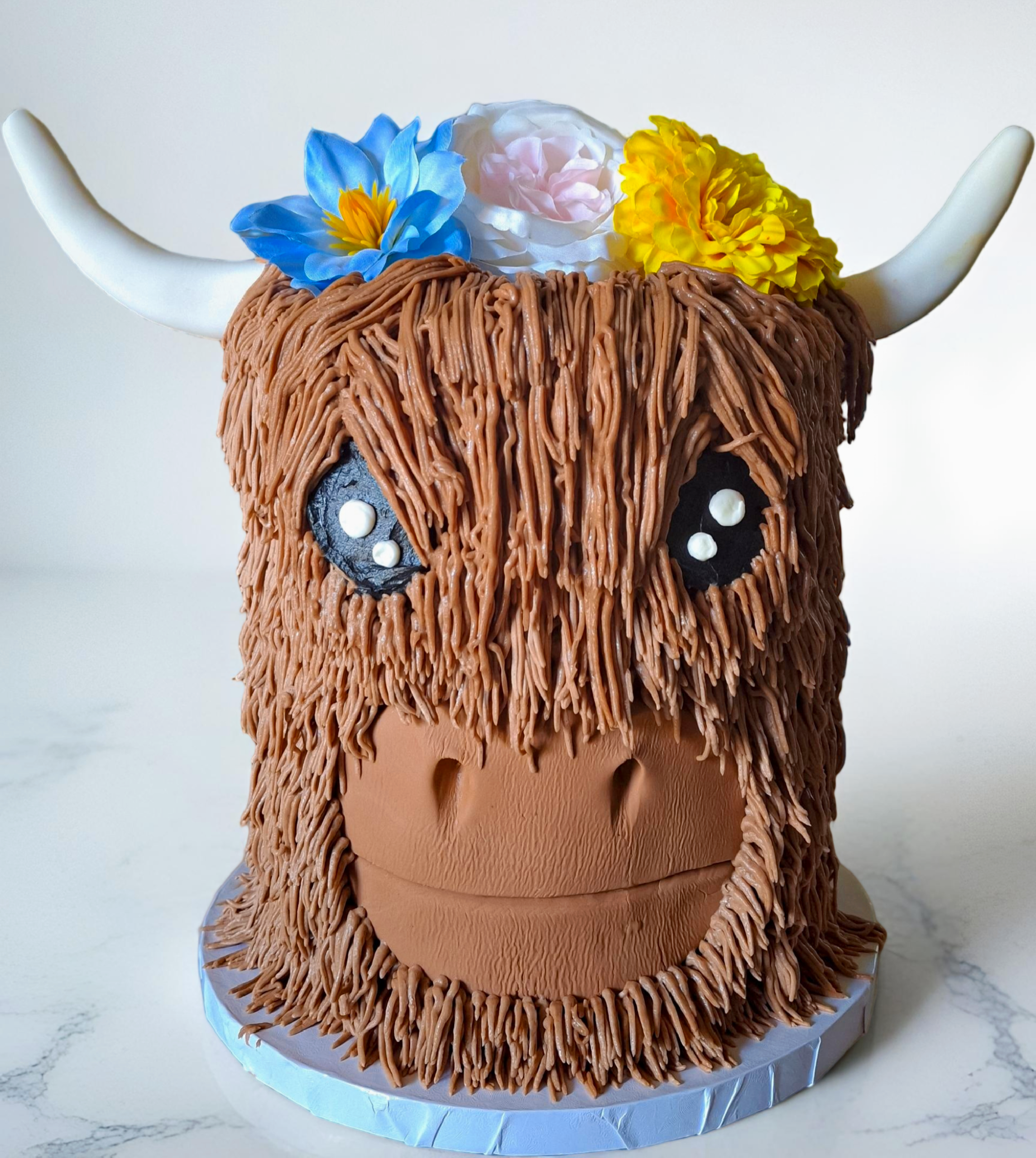 Whimsical highland cow cake with flowers