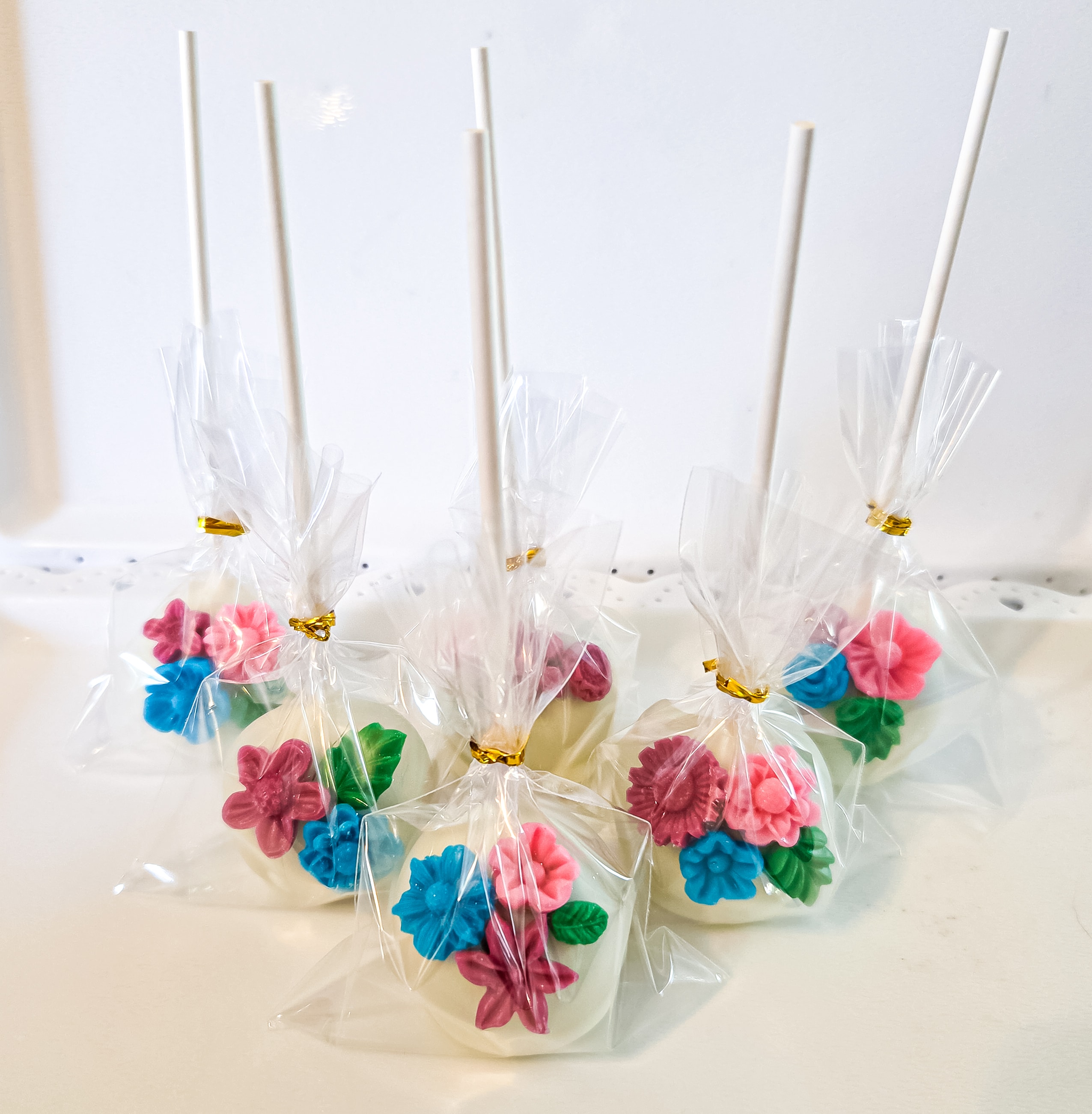 White chocolate cake pops decorated with colorful fondant flowers, individually wrapped
