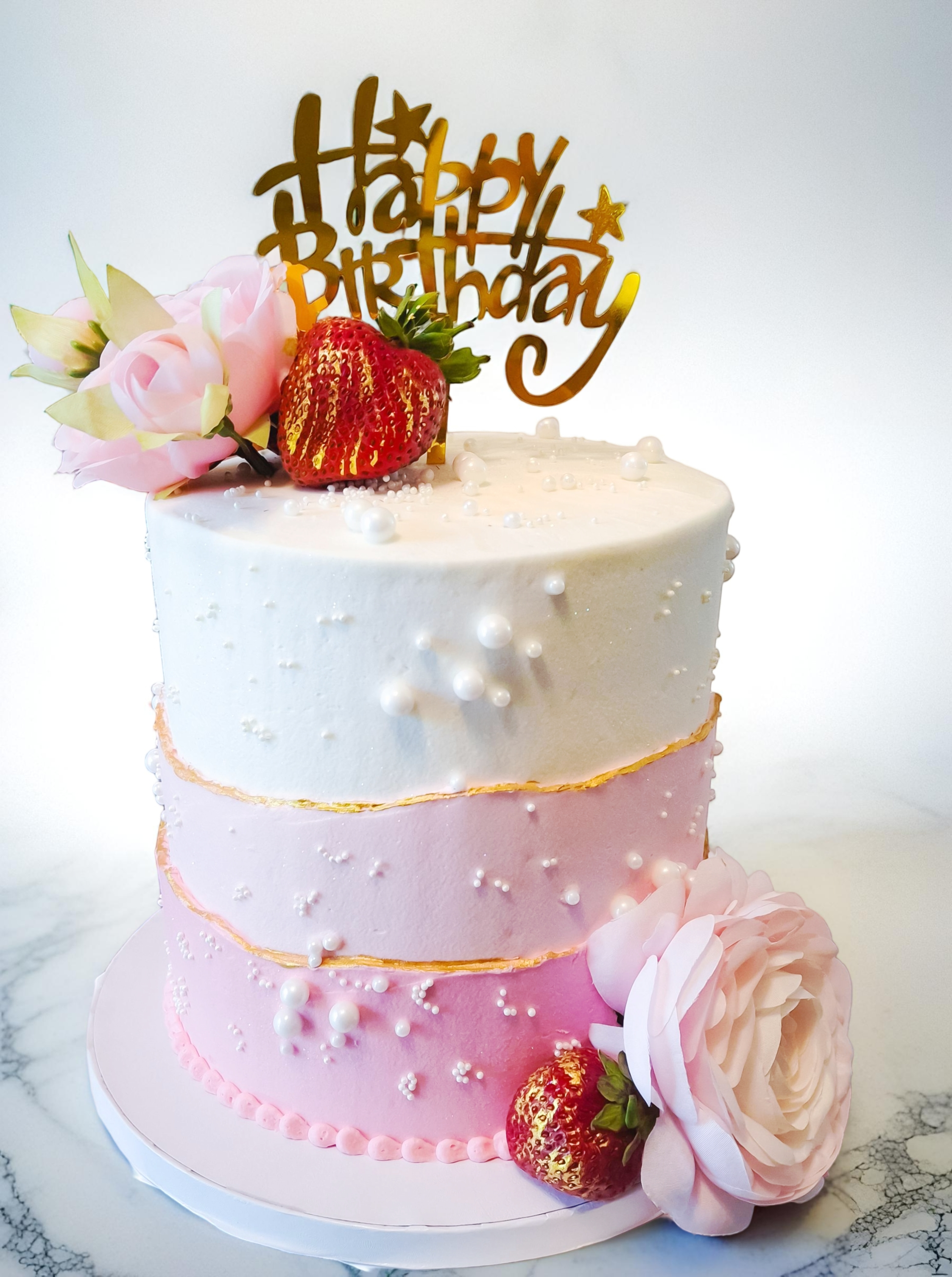 Tiered birthday cake with flowers and strawberries
